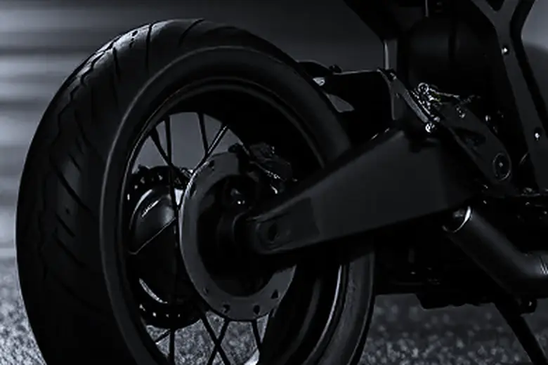 The rear wheel and swingarm on wet asphalt: the motor sits inside the hub, with no chain and no sprocket.